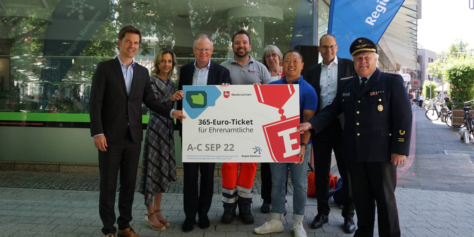 Eine Gruppe von Menschen hält ein Pappschild auf dem "365-Euro-Ticket für Ehrenamtliche" steht